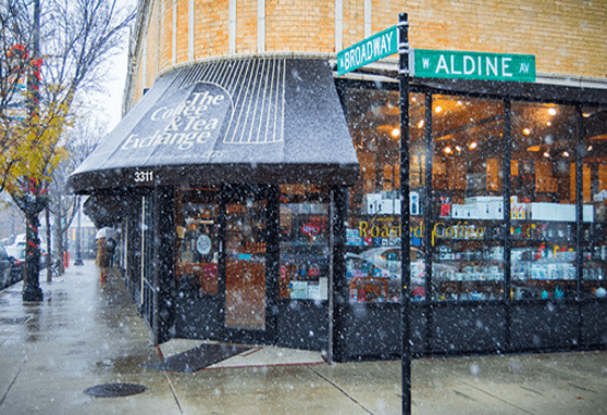 Snowy storefront of The Coffee & Tea Exchange, Corner of Aldine and Broadway, Chicago, Gold sign read 'Fresh Roasted Coffee Since 1975'